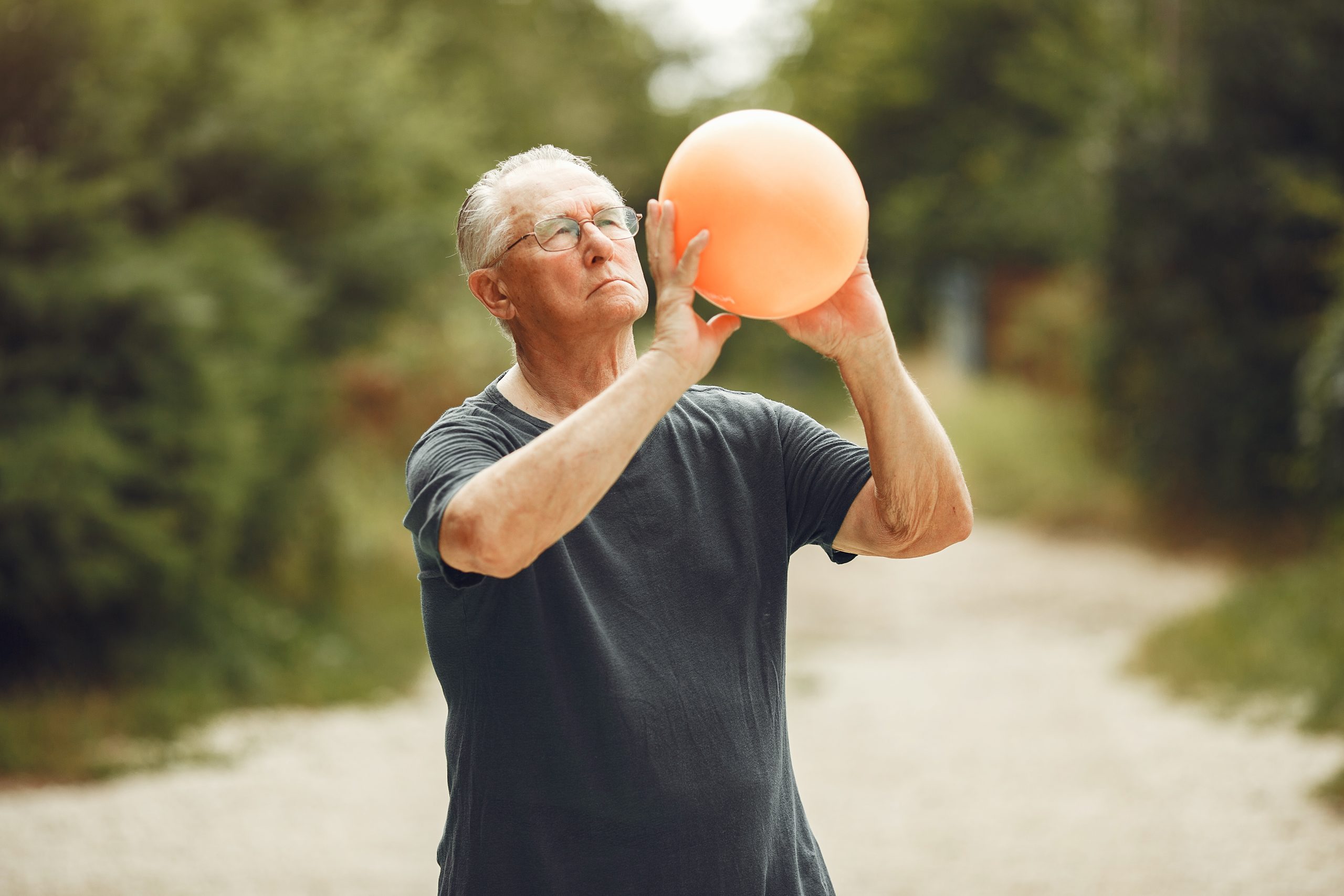 Senior man at summer park. Grangfather using a ball.